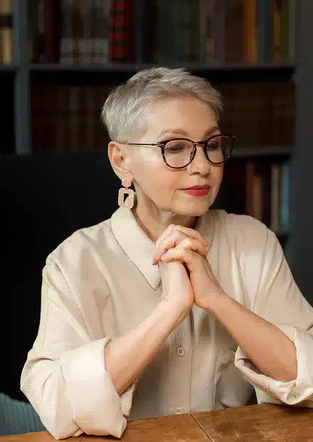 A woman wearing glasses sits at a table